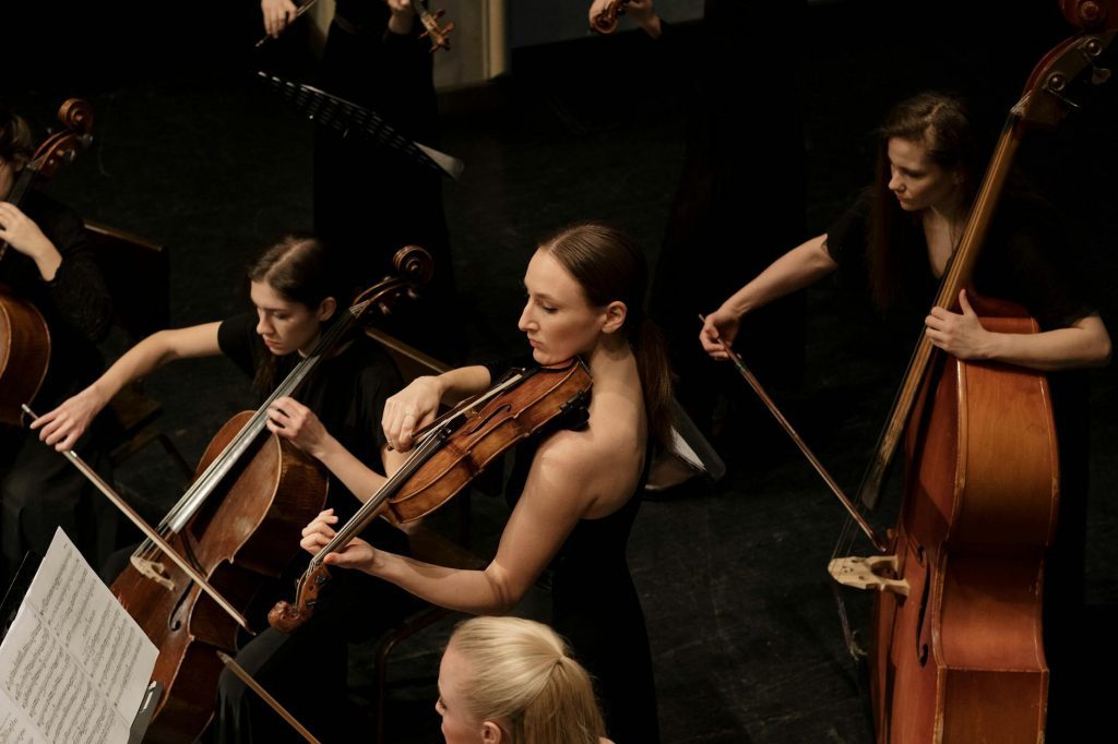 A group of female musicians playing string instruments during an indoor concert.